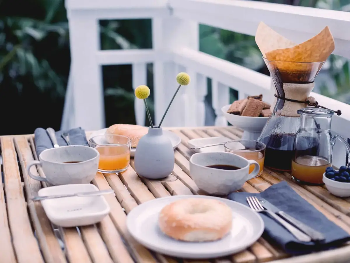 Gedeckter Frühstückstisch mit Kaffee, Saft und frischen Brötchen