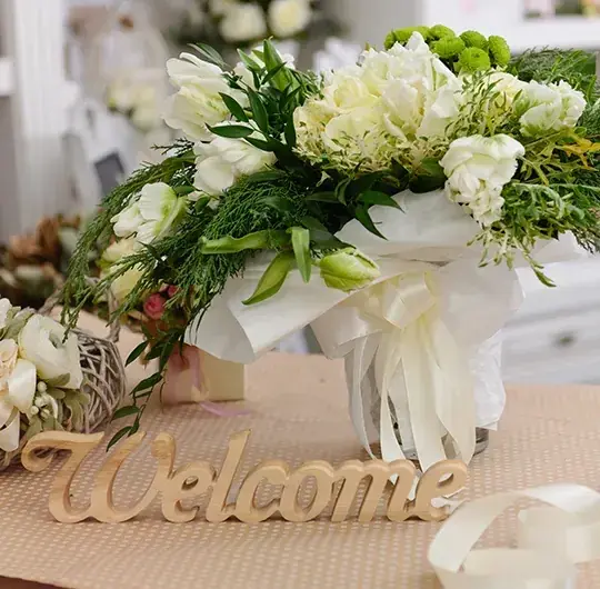 Weißer Blumenstrauß neben einem Schriftzug Welcome