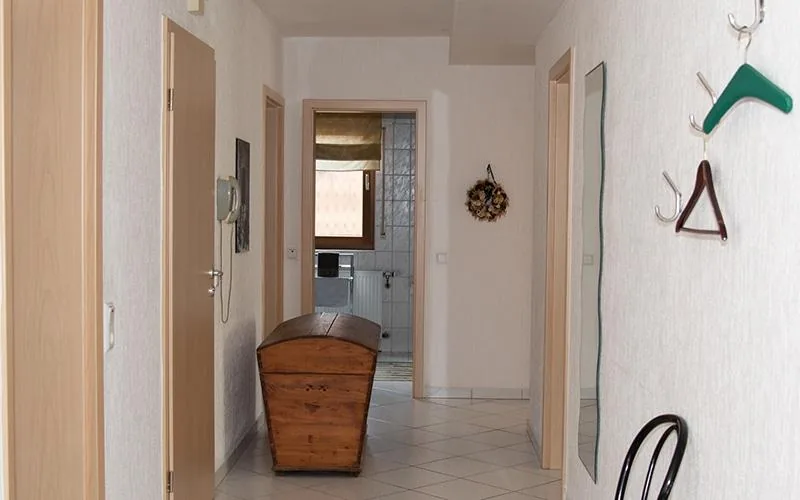 Flur der Ferienwohnung mit Garderobe, alter Holztruhe und Blick ins Bad