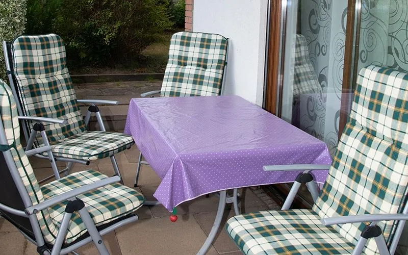 Überdachte Terrasse mit Gartentisch und vier gepolsterten Klappstühlen