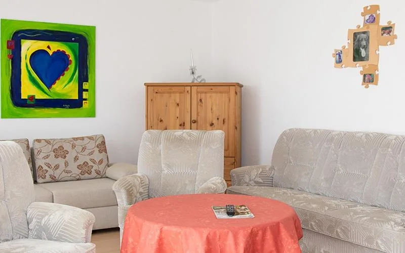 Wohnzimmer der Ferienwohnung mit heller Polstergarnitur und rundem Tisch